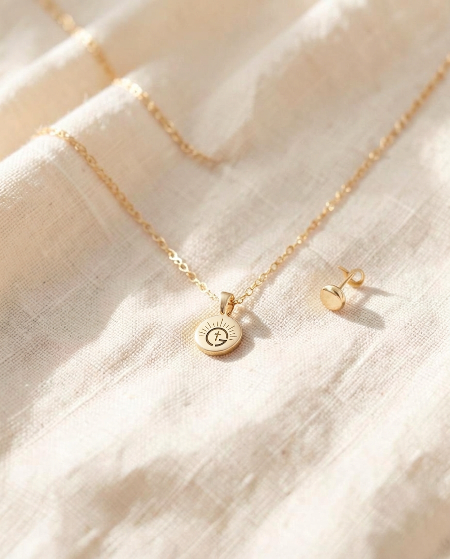 Gold GODISNU pendant necklace and earrings on linen